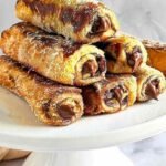 Roulés façon pain perdu saupoudrés de sucre et cannelle servis avec des fruits frais