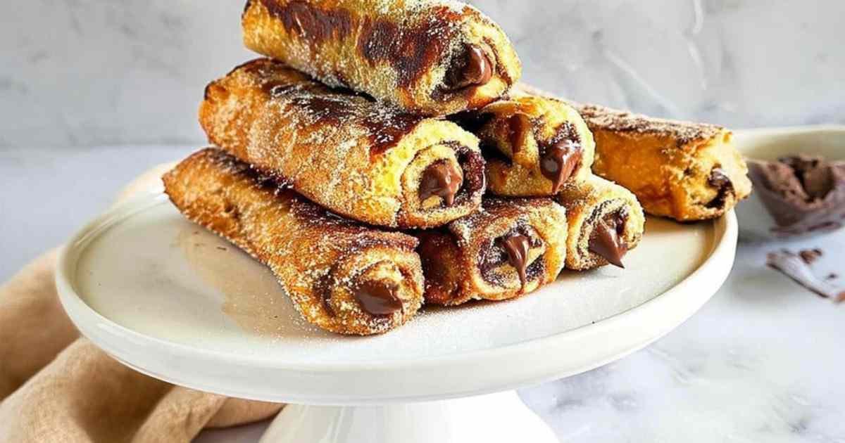 Roulés façon pain perdu saupoudrés de sucre et cannelle servis avec des fruits frais