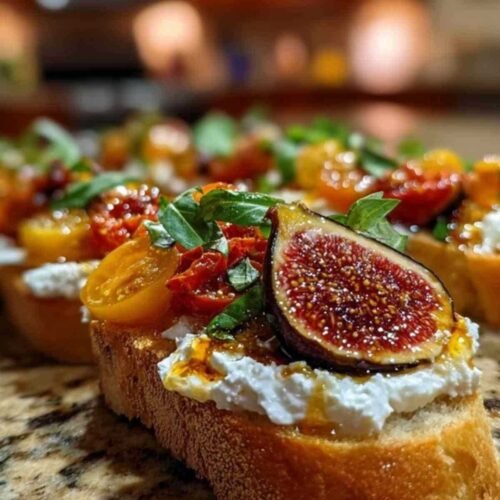 Plat de service présentant plusieurs bruschettas burrata figues garnies de basilic frais.