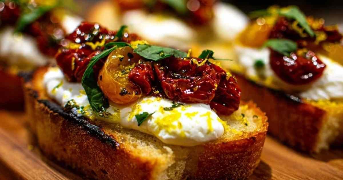 Gros plan sur une bruschetta individuelle montrant la texture crémeuse de la burrata coulant sur les tomates confites.