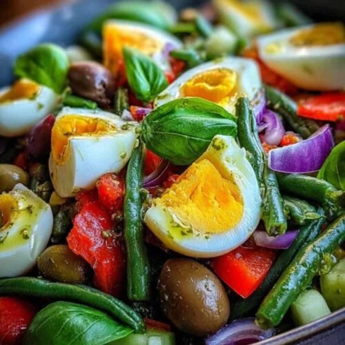 Salade tunisienne colorée servie dans un grand saladier blanc, garnie d'œufs et de basilic.