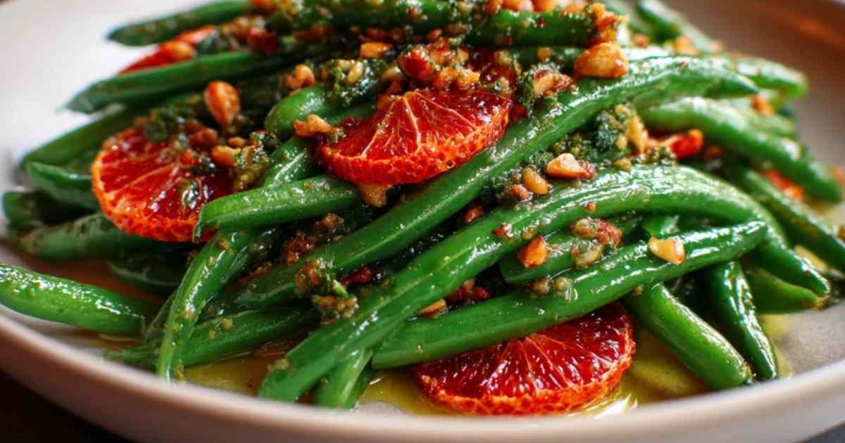 Mélange des haricots verts, des oranges sanguines et du pesto de noisette dans un grand saladier.