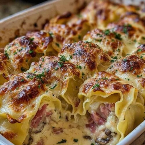 Main en train de rouler une feuille de lasagne fraîche garnie d'une farce au jambon et aux champignons sur un plan de travail en bois.