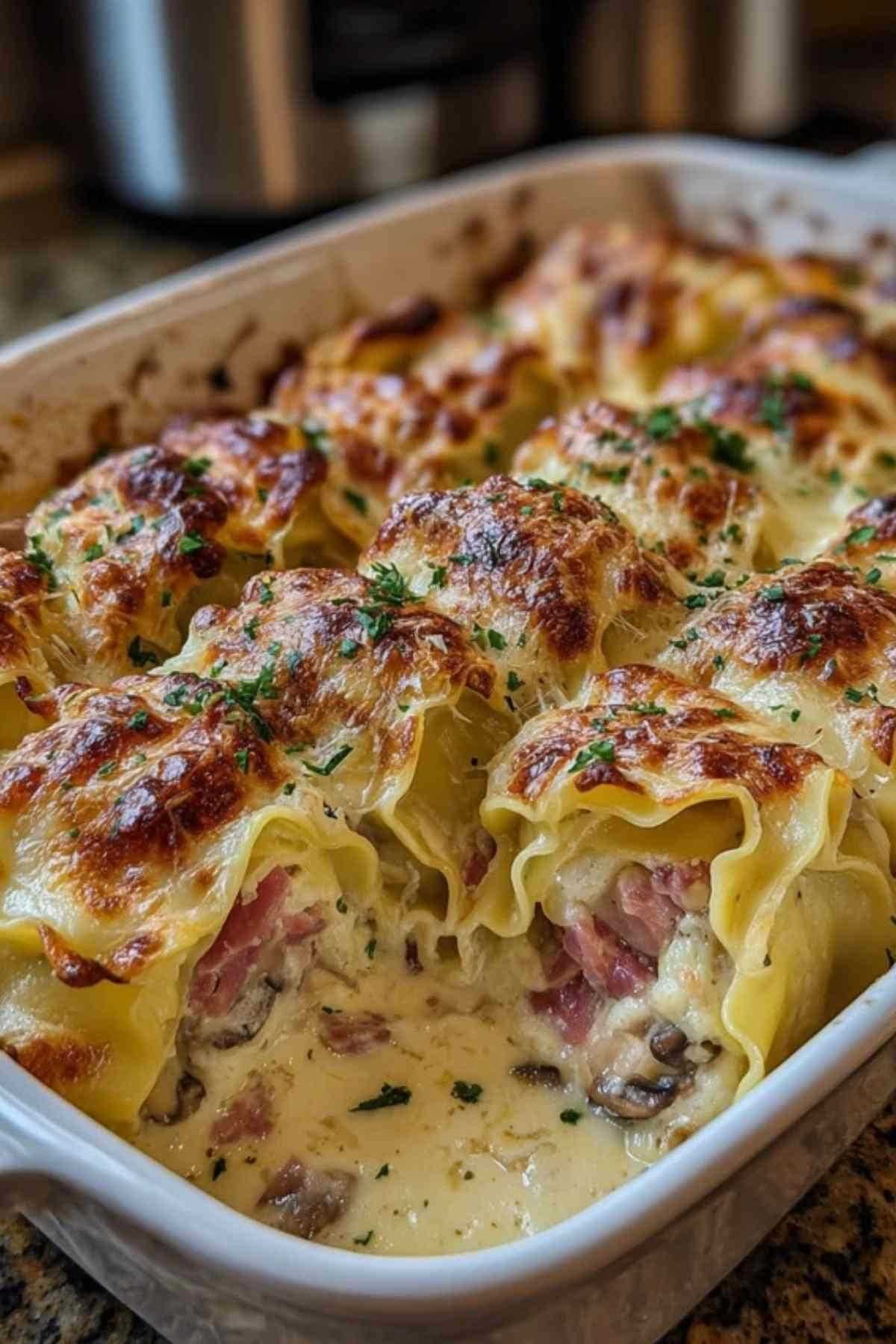 Main en train de rouler une feuille de lasagne fraîche garnie d'une farce au jambon et aux champignons sur un plan de travail en bois.