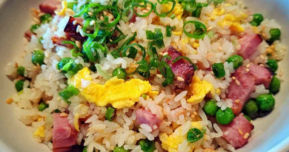 Gros plan du riz cantonnais en train de sauter dans un wok chaud avec une spatule.