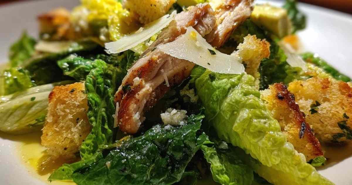 Gros plan sur les copeaux de parmesan et les croûtons dorés dans la salade césar estivale.