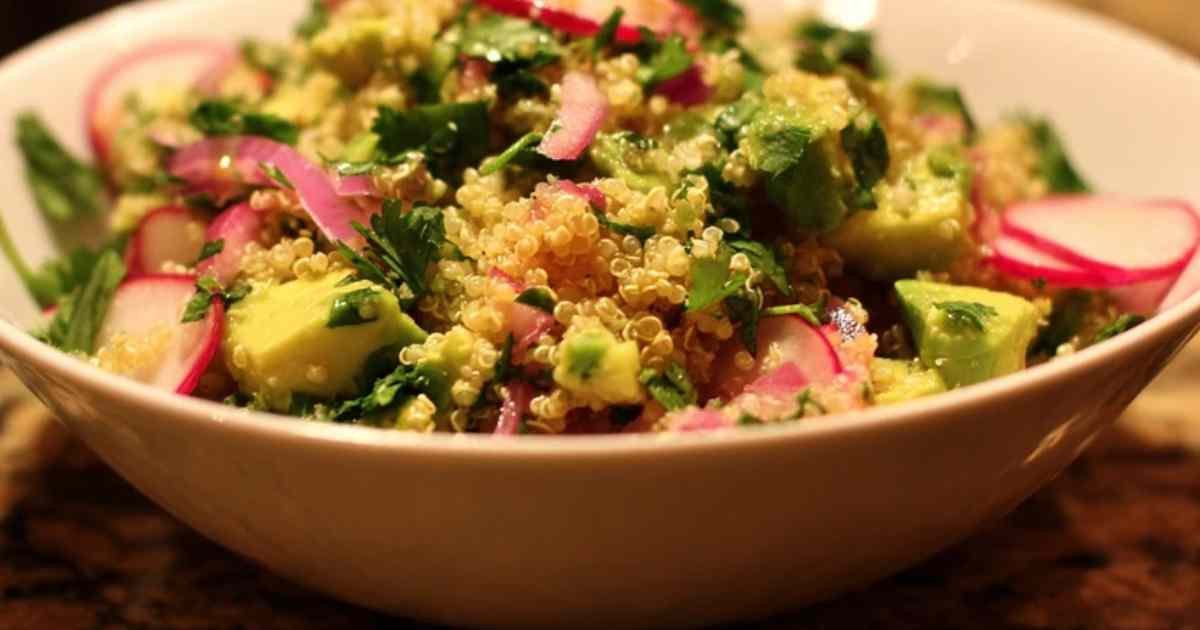 Salade de quinoa, avocat, radis et coriandre fraîche dans un grand saladier blanc, prête à être servie.