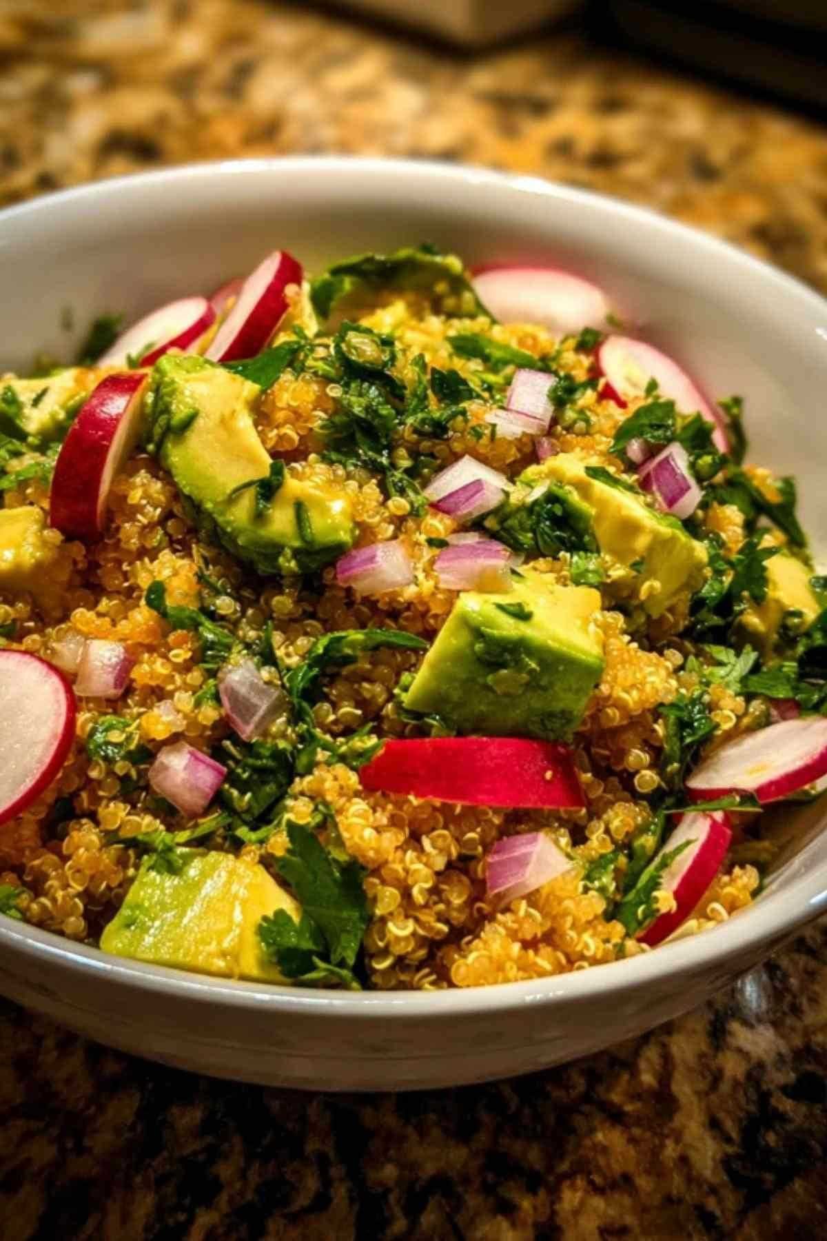 Ingrédients frais pour la salade de quinoa : quinoa, un avocat, des radis, un oignon rouge, un bouquet de coriandre et un citron vert.