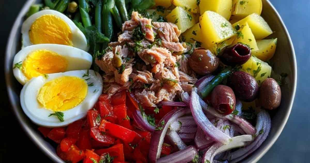 Recette de salade niçoise complète et colorée servie dans une assiette blanche.