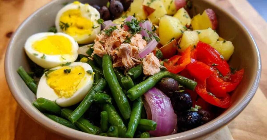 Vinaigrette maison à l'huile d'olive versée sur une salade niçoise.