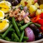 Vinaigrette maison à l'huile d'olive versée sur une salade niçoise.