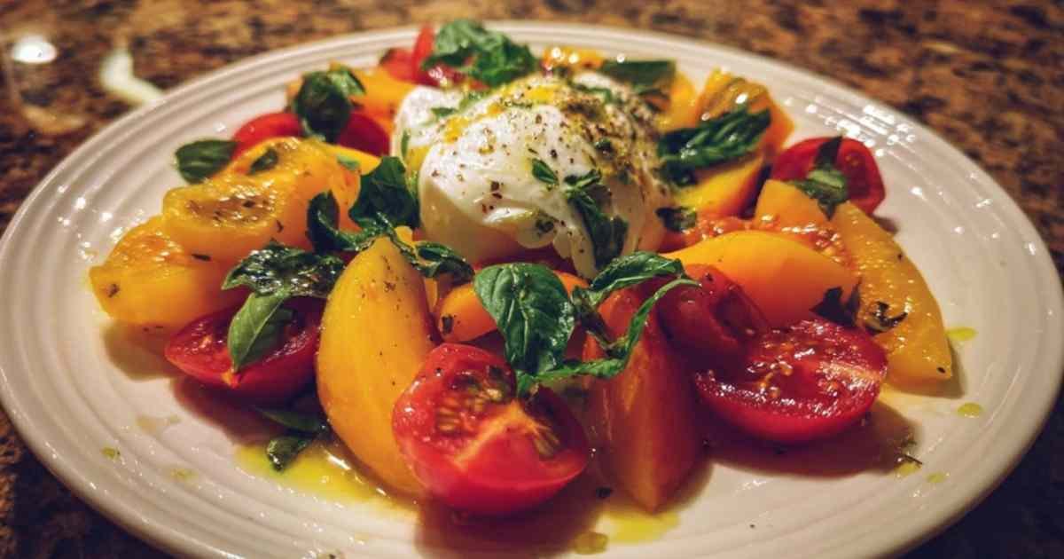 Gros plan burrata ouverte avec pêches dans salade estivale