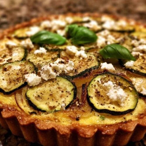 Ingrédients tarte courgette feta disposés : courgettes, feta, œufs, crème fraîche, herbes