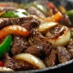 Bœuf aux poivrons chinois grésillant servi dans un wok avec oignons caramélisés