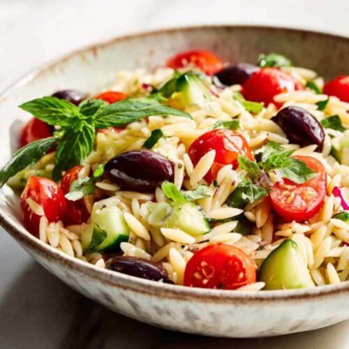 Salade de pâtes orzo colorée dans un grand saladier avec légumes frais