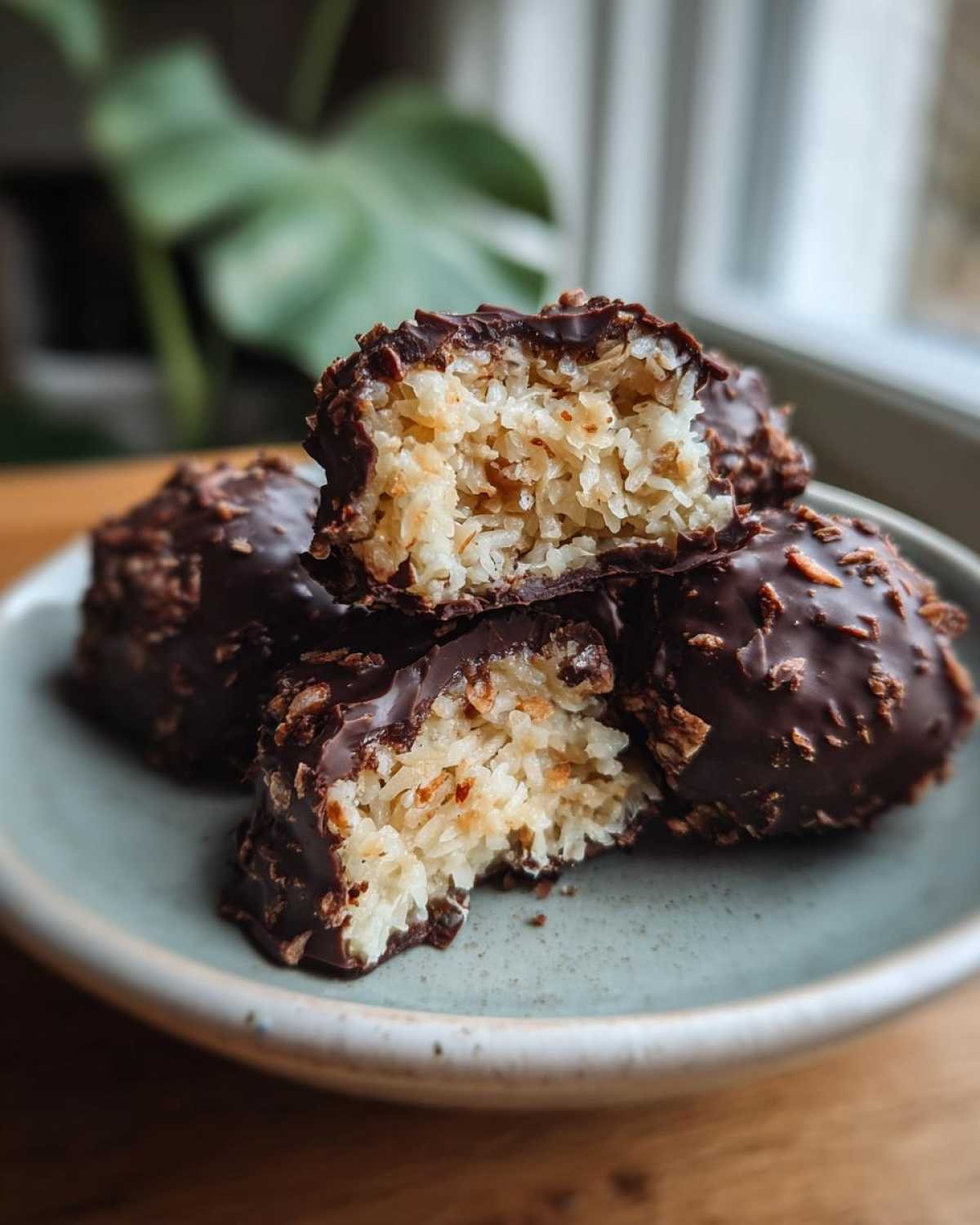 Gros plan sur des Almond Joy maison healthy coupés en deux, révélant la noix de coco et le chocolat noir.