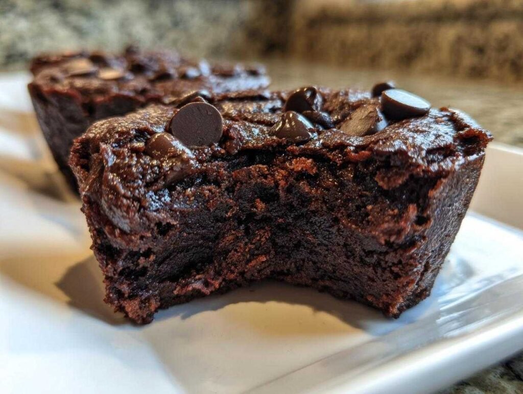 Gros plan d'un bite protéiné brownie au cottage cheese, garni de pépites de chocolat.