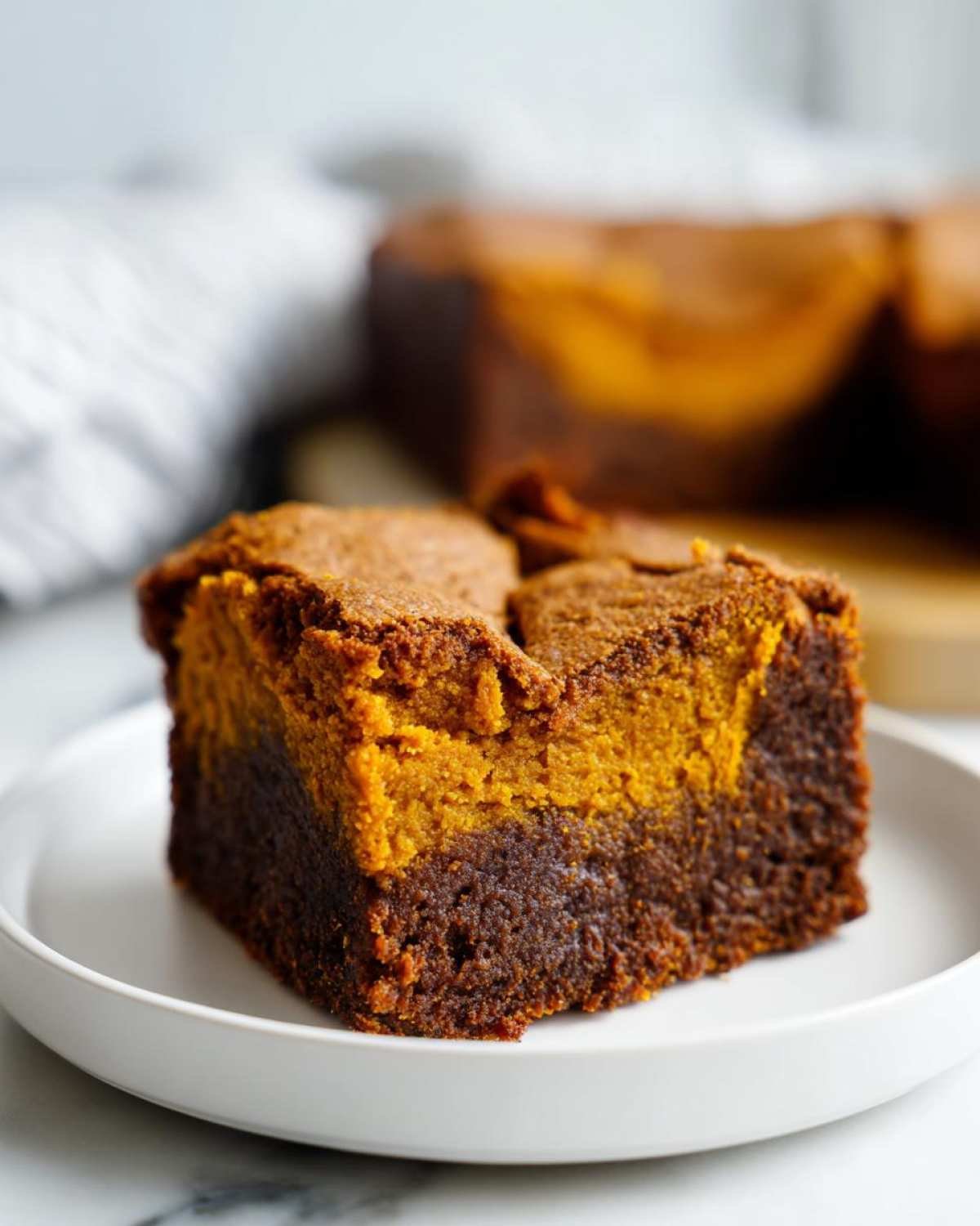 Gros plan d'une tranche de brownie citrouille 4 ingrédients, avec une couche de chocolat et une couche de citrouille.