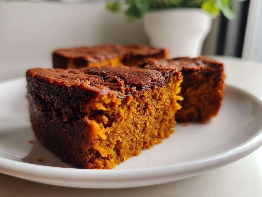 Gros plan d'une tranche de brownie citrouille 4 ingrédients sur une assiette blanche.