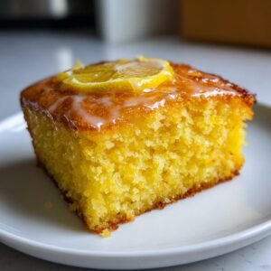 Gros plan d'un carré de brownies au citron avec un glaçage blanc et une tranche de citron confit sur le dessus.