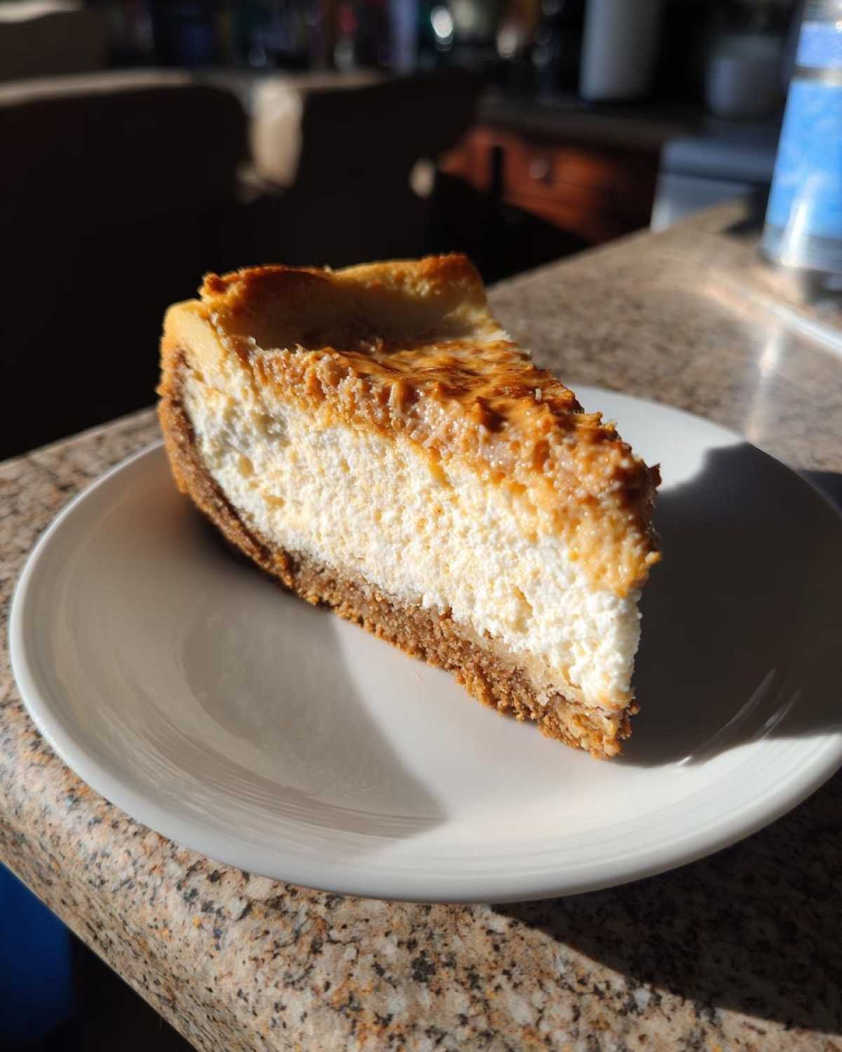 Gros plan sur une tranche de cheesecake beurre cacahuète keto sur une assiette blanche.