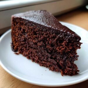 Gros plan d'une part de gâteau chocolat keto ultime, avec un glaçage brillant et une texture moelleuse.
