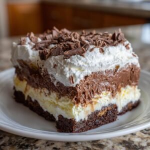 Gros plan d'une tranche de Gâteau Réfrigéré aux Brownies avec crème fouettée et copeaux de chocolat.