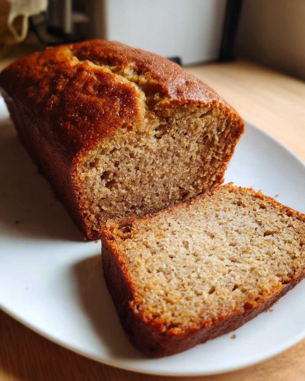 Une tranche de pain de banane facile et moelleux sur une assiette blanche.