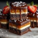 Gros plan de barres caramel chocolat empilées, garnies de chocolat, caramel, fraise et sel de mer.