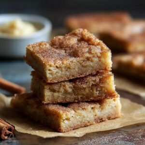 Trois blondies au miel et à la cannelle empilés, saupoudrés de sucre à la cannelle.