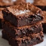 Gros plan sur une pile de brownies fondants au chocolat, saupoudrés de sucre glace.