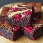 Gros plan sur des brownies framboise marbré avec des framboises et un marbrage au chocolat et à la crème.