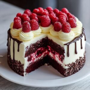 Gâteau Chocolat Blanc Framboise Facile avec une part coupée, garni de framboises fraîches et de crème.