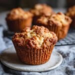 Gros plan sur un muffin moelleux aux pommes, avec d'autres muffins en arrière-plan.