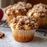 Gros plan sur un muffin pomme cannelle streusel, garni d'une généreuse couche de streusel croustillant.