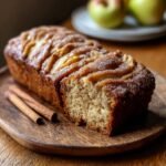 Gros plan d'un pain au cidre de pomme et cannelle, garni de tranches de pomme et de sucre.