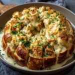 Gros plan d'un Pain Singe au Poulet Alfredo, garni de fromage fondu et de persil frais.