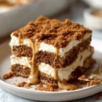 Gros plan d'une part de Tiramisu Biscoff Spéculoos crémeux, garni de miettes de spéculoos et d'un coulis caramel.