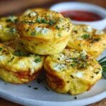 Gros plan sur des bouchées d'œufs au fromage cottage dorées, garnies d'herbes fraîches.