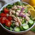 Salade de thon et haricots blancs avec tomates cerises, concombre, oignon rouge et quartiers de citron.